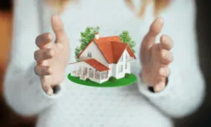 una donna con maglia bianca di cui non si vede il viso tiene tra le mani una casetta